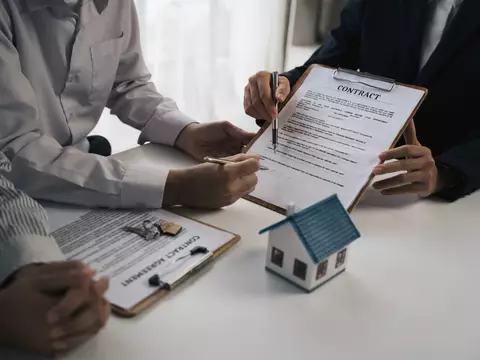 Signature d'un contrat à côté d'une maquette de maison